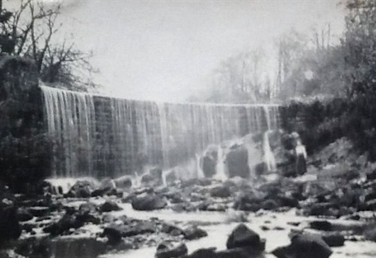 Photo:Meg Haig standing (left) at the foot of the Limefield Falls, re-modelled by James Young as a miniature Victoria Falls in honour of his friend, David Livingstone.  c.1917.