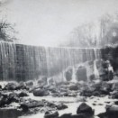 Photo:Meg Haig standing (left) at the foot of the Limefield Falls, re-modelled by James Young as a miniature Victoria Falls in honour of his friend, David Livingstone.  c.1917.