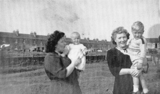 Photo:Margaret (left) and Betty Hamilton with a friend's children, Susanne and John Dunleavy.  Taken in front of Addiewell Pond.  In the background, Livingstone Street.  1950s.