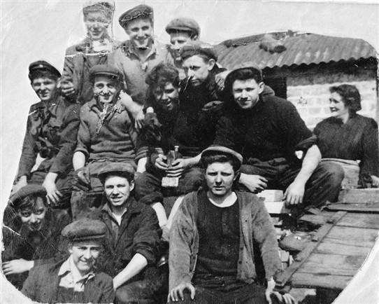 Photo:Loganlea Colliery miners.  In the background, Sarah Thomson, who worked on the tables, sorting out stones from the coal. Nearest to her, in dark shirt, Tommy Curran.